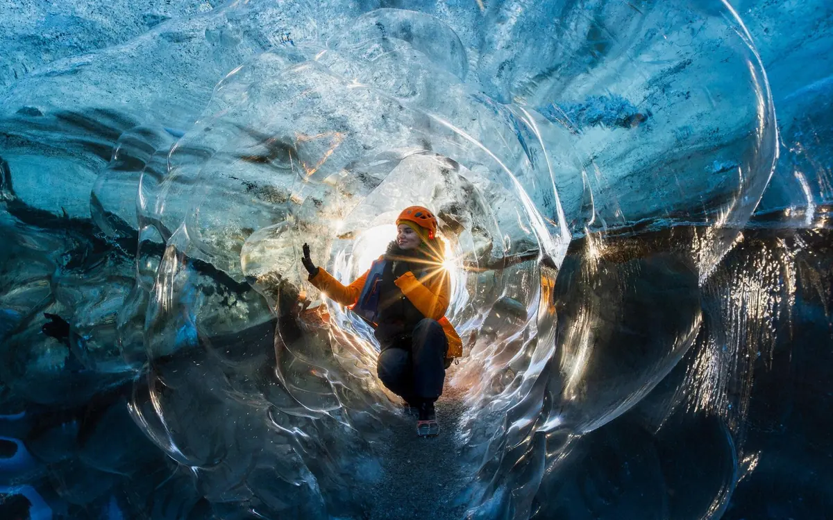 Przewodnik stojący przy wejściu do naturalnej jaskini w lodzie Vatnajökull