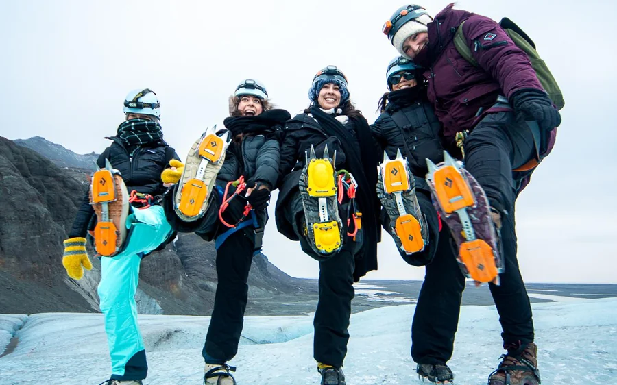 Eine Gruppe auf dem Eis hält Helme und Steigeisen bereit, bevor es losgeht