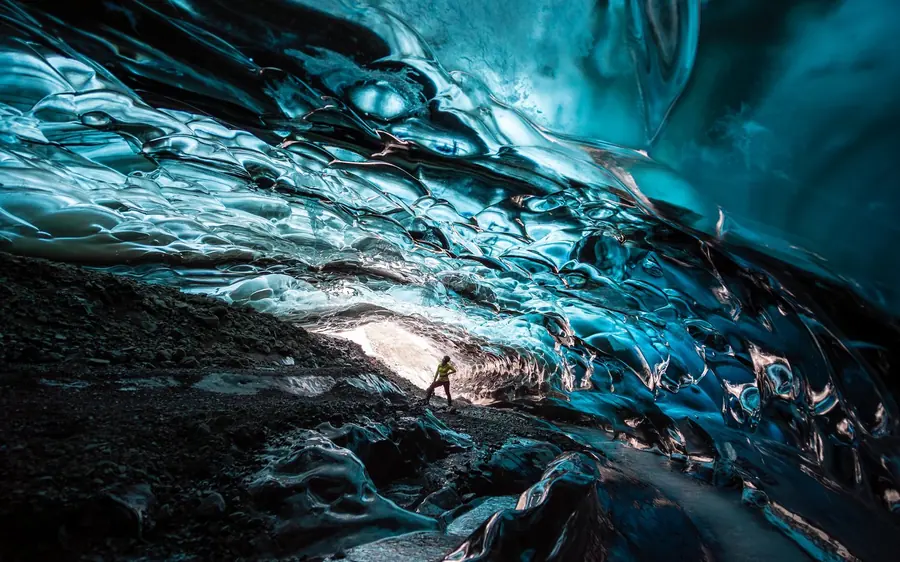 Tageslicht am Ende einer blauen Eishöhle mit gewelltem Gewölbe